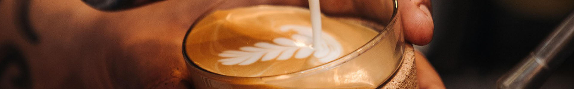 cappuccino eingießen von barista mit muster im schaum